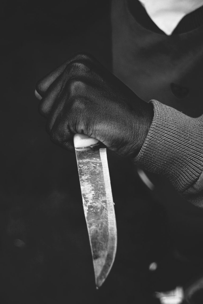 a grayscale of a person holding a knife